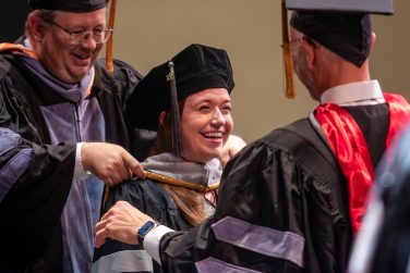 Associate Dean for Academic and Student Affairs Timothy Snider hoods Jennifer Hoover with assistance from Chair of Veterinary Medicine and Surgery John Dodam.  The students selected Dodam to assist with the investiture ceremony.