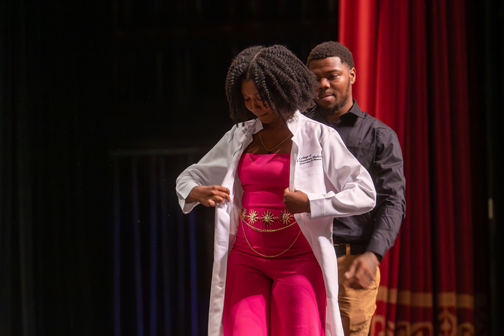 Keisha Gray dons her white laboratory coat, presented by her brother Keith Gray. 