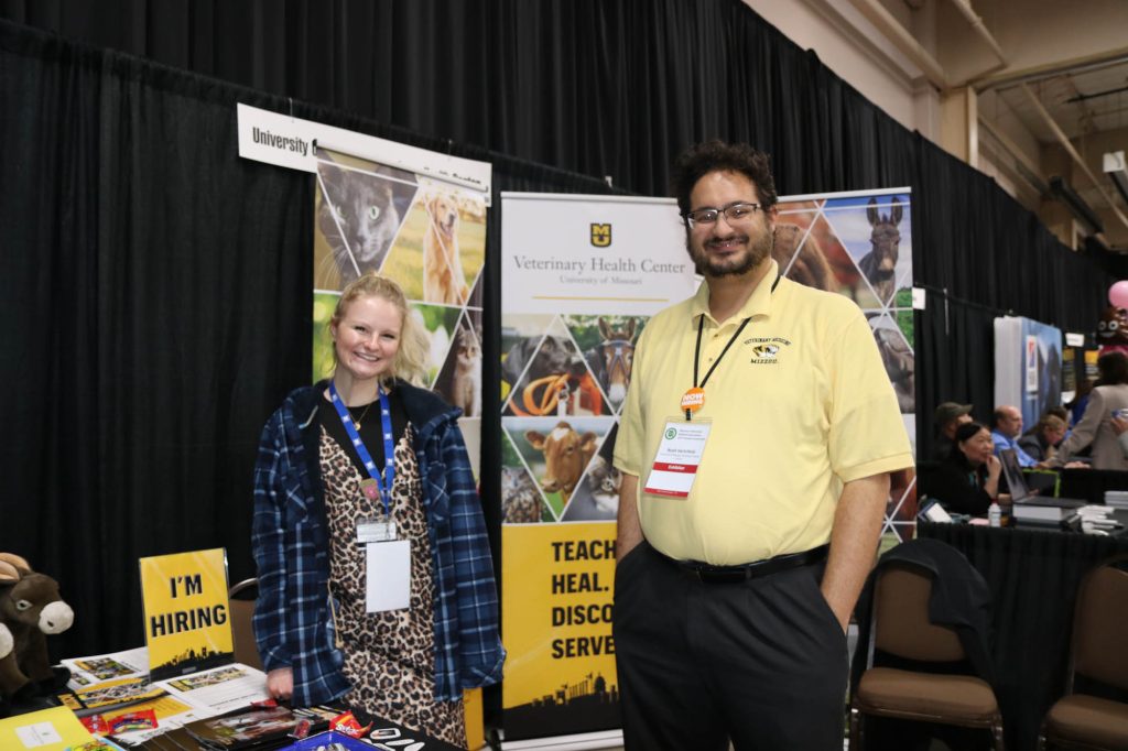 two people smile at a booth