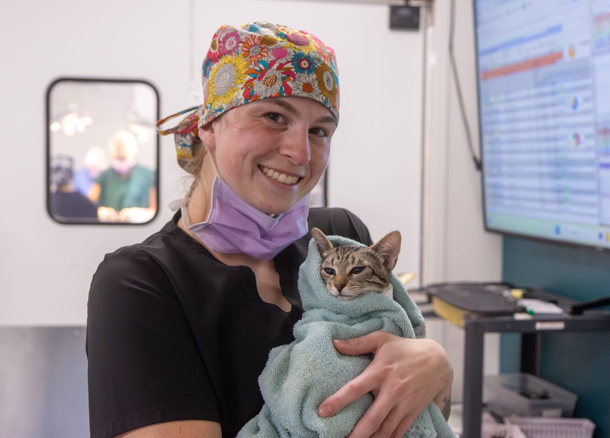A woman in scrubs holding a cat