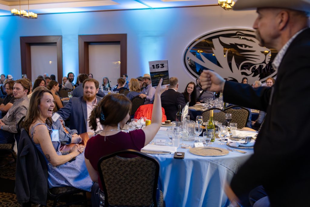people smiling and bidding during live auction