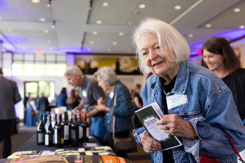 an event-goer looks at silent auction items and smiles