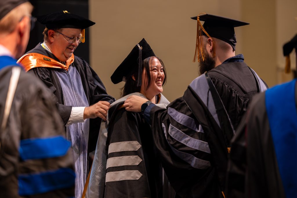 a student smiles while being hooded 