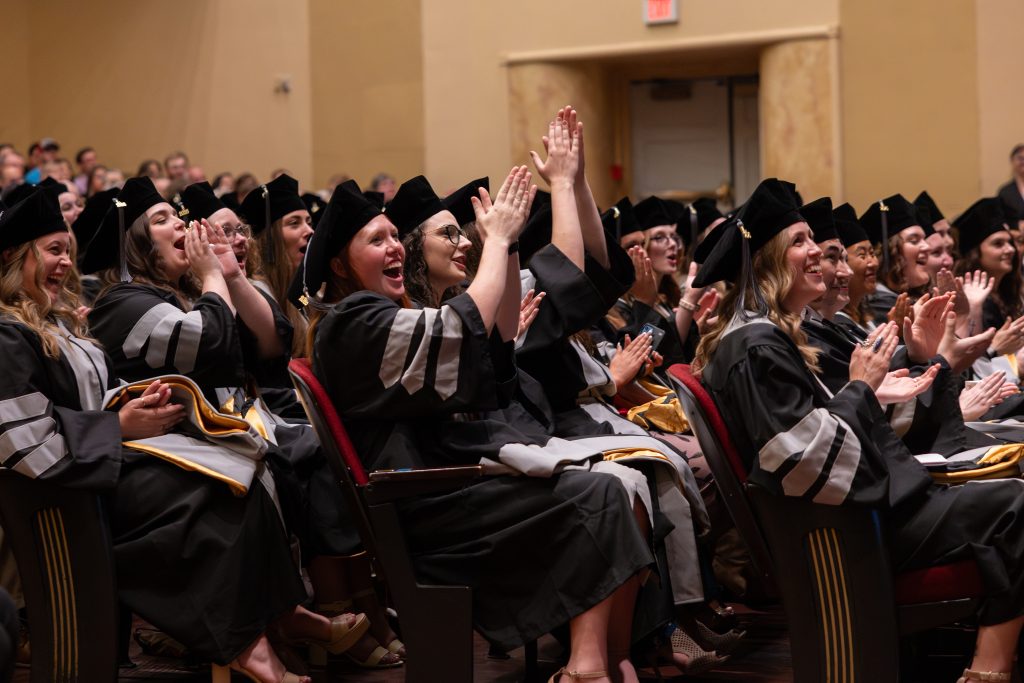 students clap during commencement