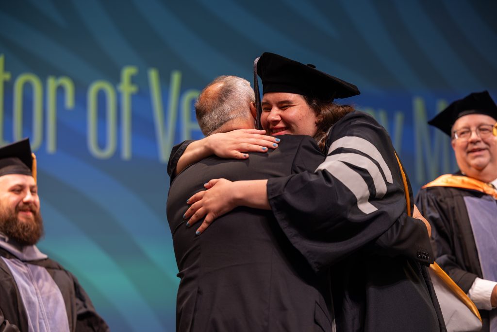 a graduate hugs someone on stage