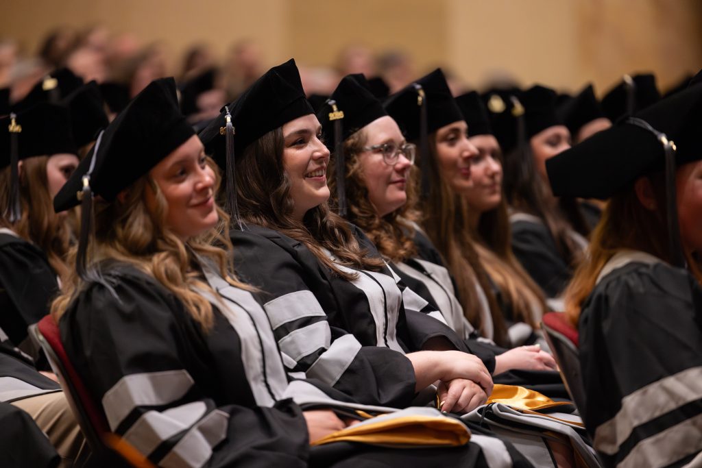 students smile and listen to graduation speakers