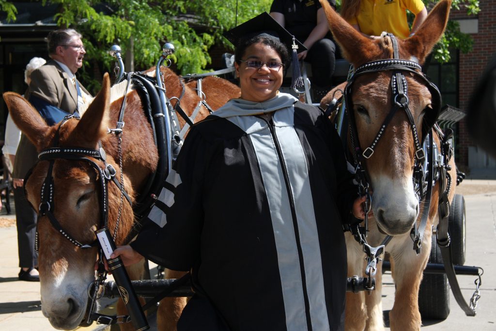 Rowena Woode in a graduation gown photographed with two mules.
